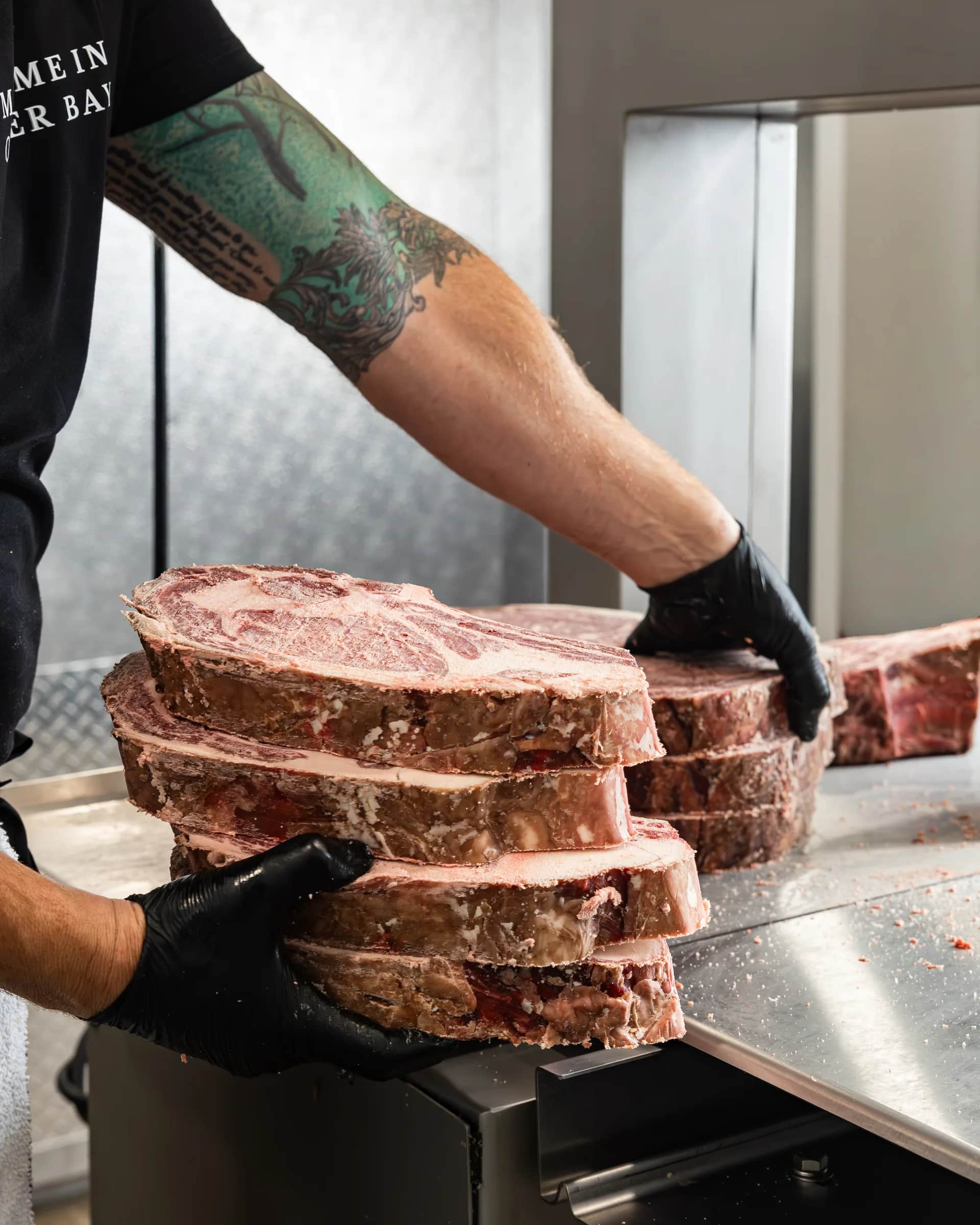 Tattooed arm placing a steak on the stack