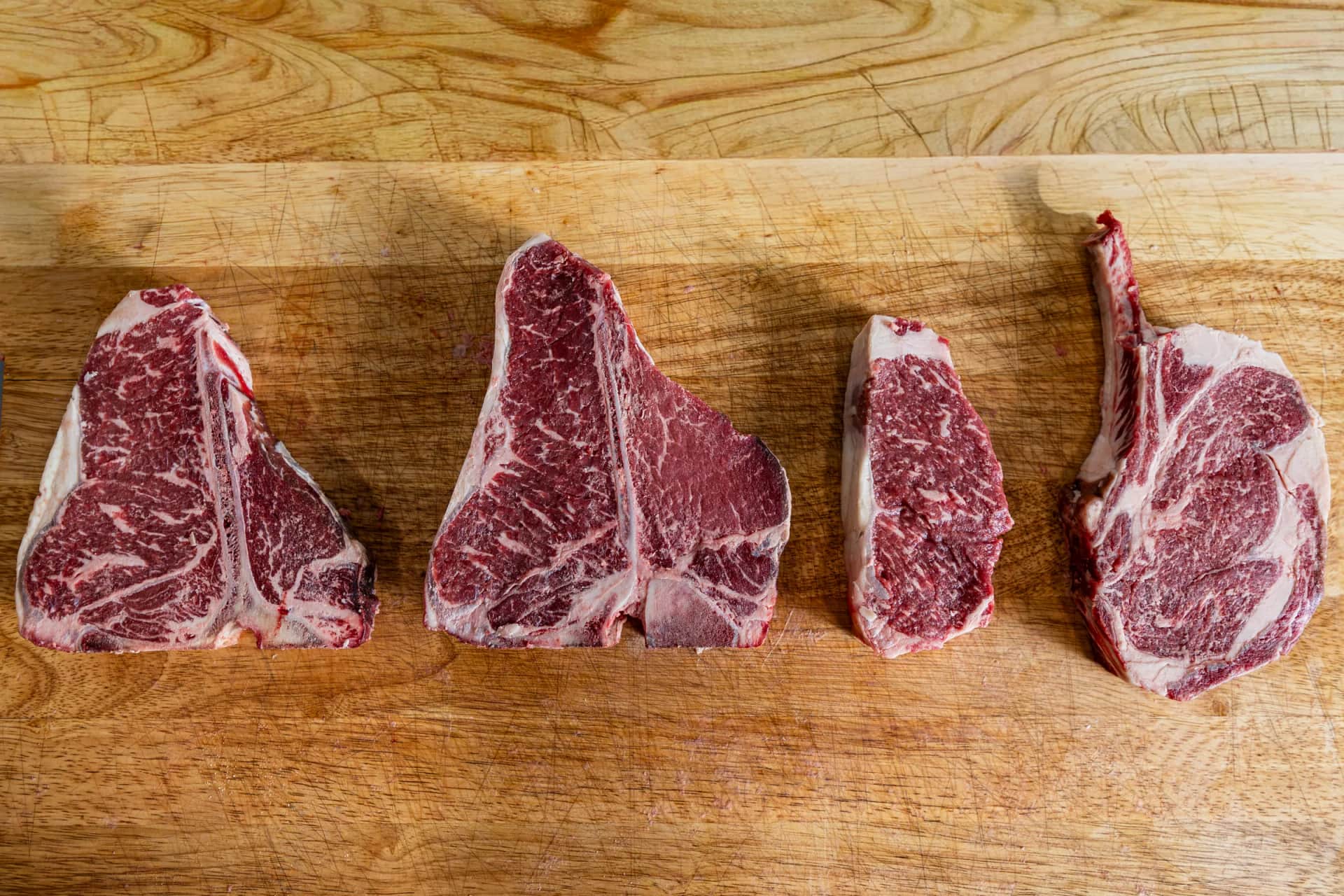 Porterhouse, T-bone, and tomahawk lineup on the board