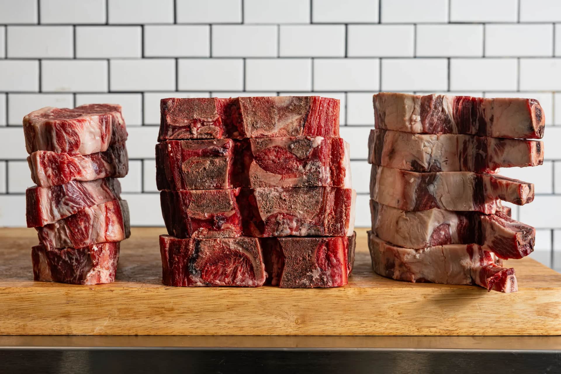 Three steak stacks on a wooden board