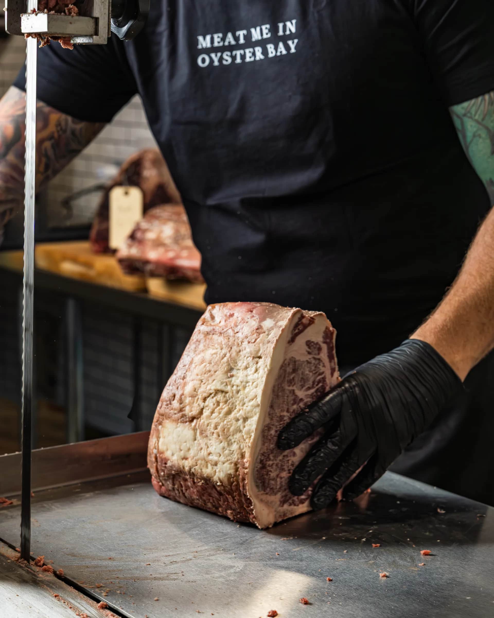 The Bay Butcher tee at the band saw with a dry-aged loin