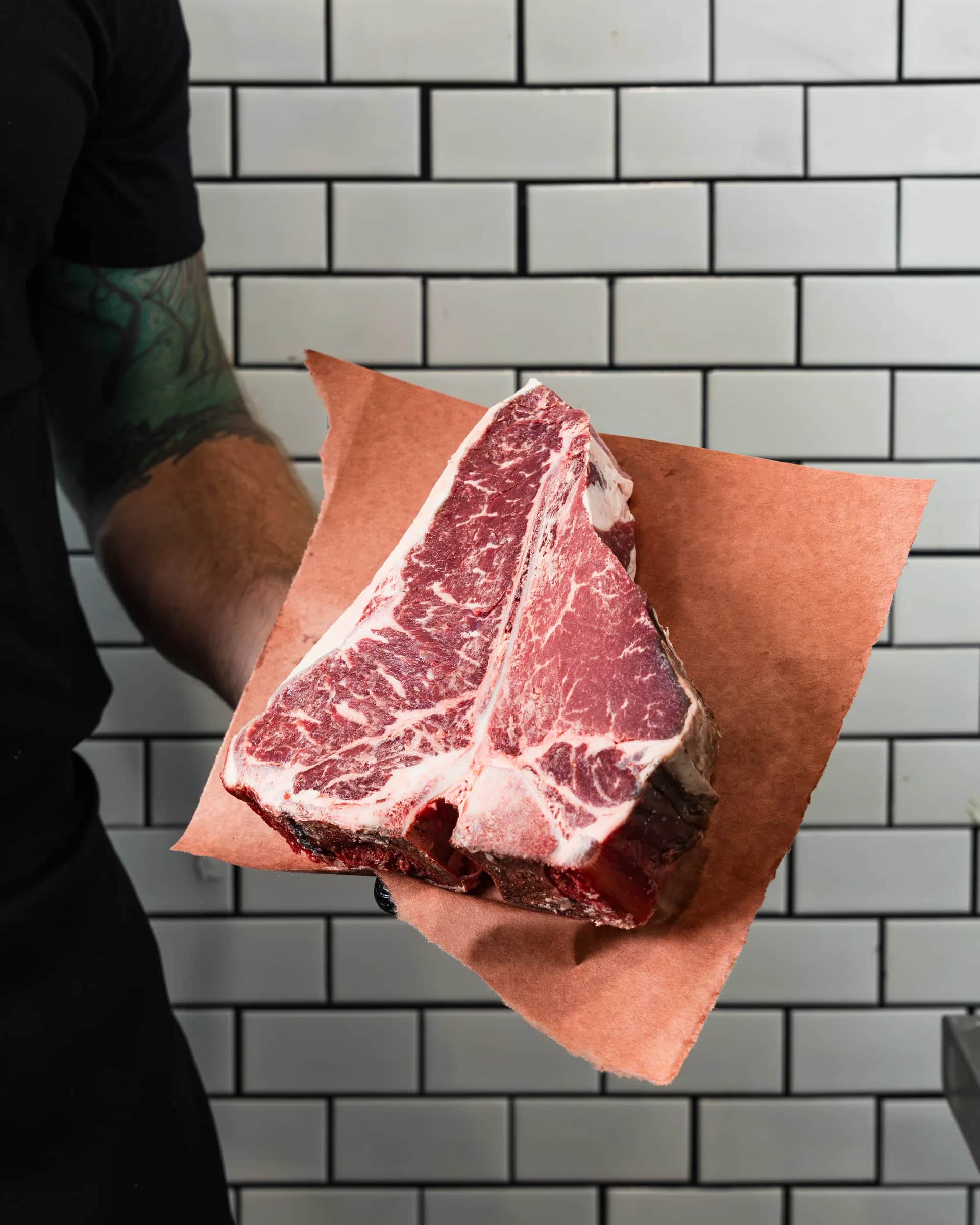 Porterhouse presented on butcher paper against subway tile