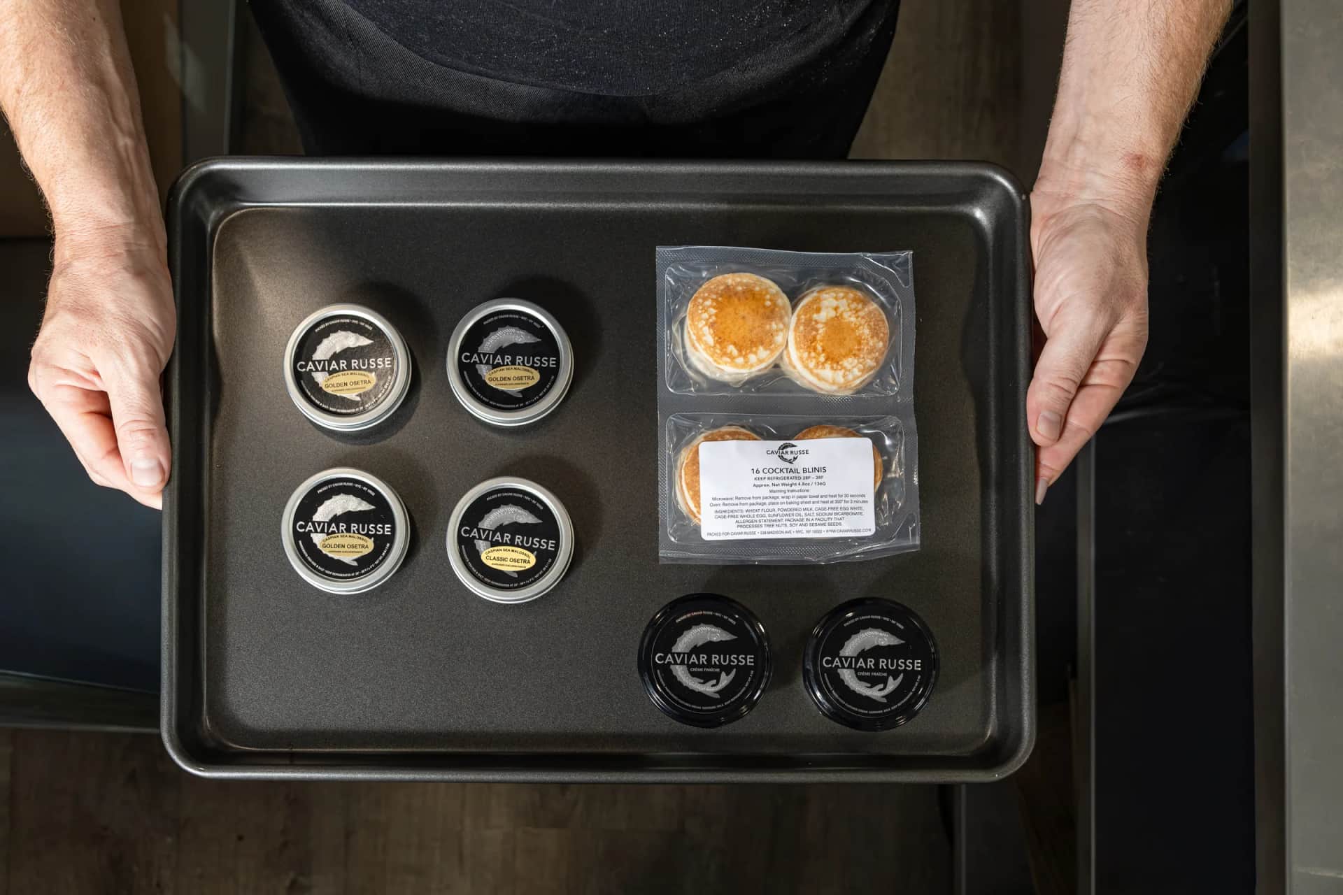Overhead of Caviar Russe tins and blinis