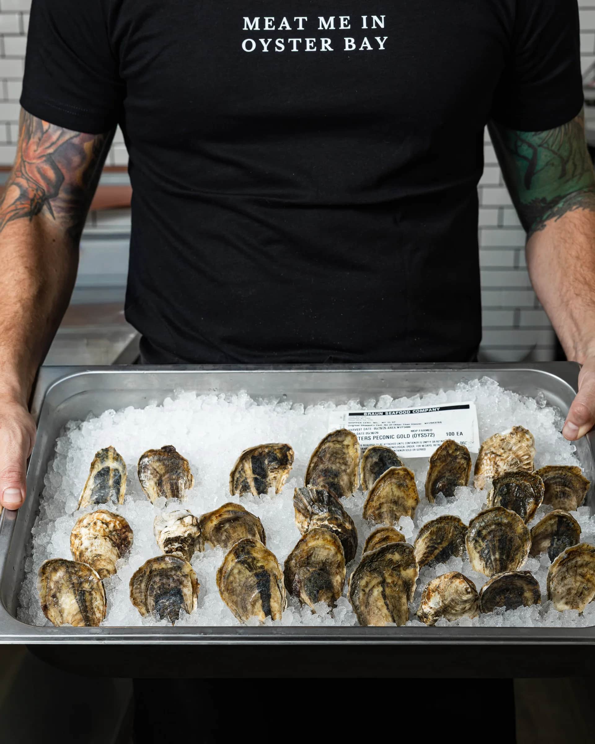 A tray of fresh oysters on crushed ice, held at the counter